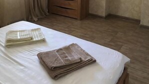 A hotel room with a bed, a wooden dresser, a flat-screen TV mounted on the wall, and a window with curtains. - Veni Vedi guesthouse  (Vedi)