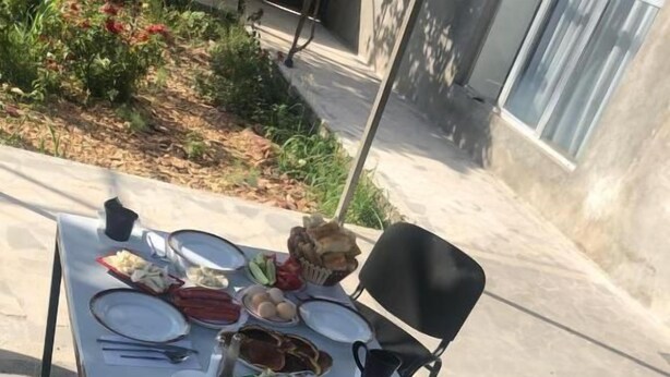 An outdoor dining table set with plates, cutlery, a basket of bread, a bowl of fruit, and beverages. - Veni Vedi guesthouse  (Vedi)