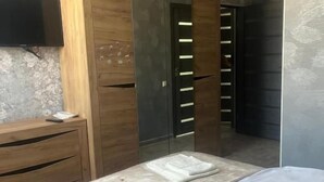 A bedroom with a bed, a wooden wardrobe, a television, and a mirror. - Veni Vedi guesthouse  (Vedi)