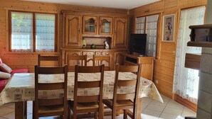 Ein Holzkamin mit einem Esstisch, Stühlen und einem Fernseher.