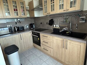 A modern kitchen with wooden cabinets, stainless steel appliances, and a tiled backsplash. - Vrbo Property (DINARD)