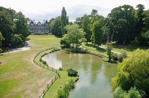 A large, landscaped property with a central pond, surrounded by manicured lawns and trees. - Le Botéro - Cozy 2-bedroom apartment, 2 bedrooms, balcony & garage (DINARD)