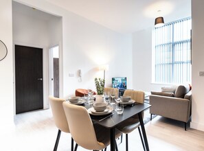 Ein stilvoller Essbereich mit einem Tisch für vier Personen, einer Couch und einem Fernseher.