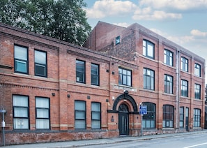 A red brick building with multiple windows and a black door. - Apex House by Guestz (Warrington)