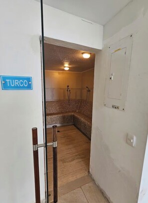Ein Zimmer mit einem Schild mit der Aufschrift 'TURCO', einer Duschkabine mit gefliesten Wänden und einem Holzboden.