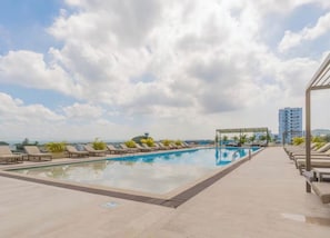 Una piscina sul tetto con lettini e un pergolato.