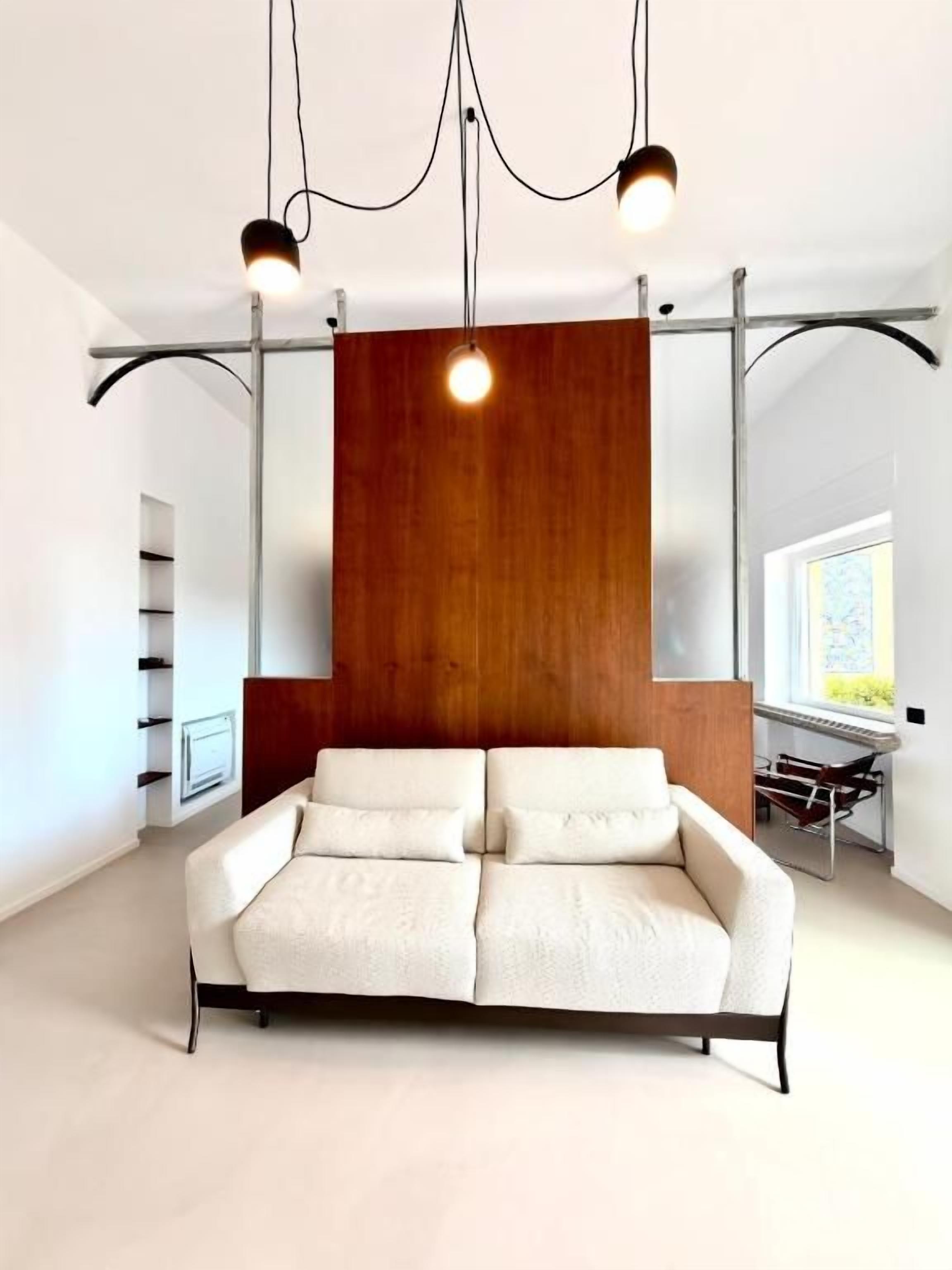 A modern living room with a sofa, pendant lights, and a wooden accent wall.