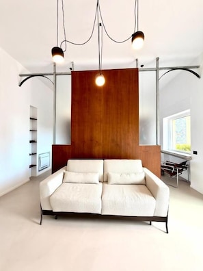 A modern living room with a sofa, pendant lights, and a wooden accent wall.