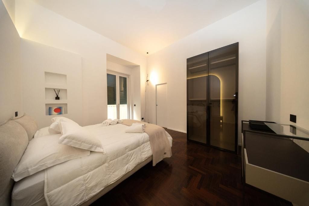 A modern bedroom with a bed, a desk, and a walk-in closet.
