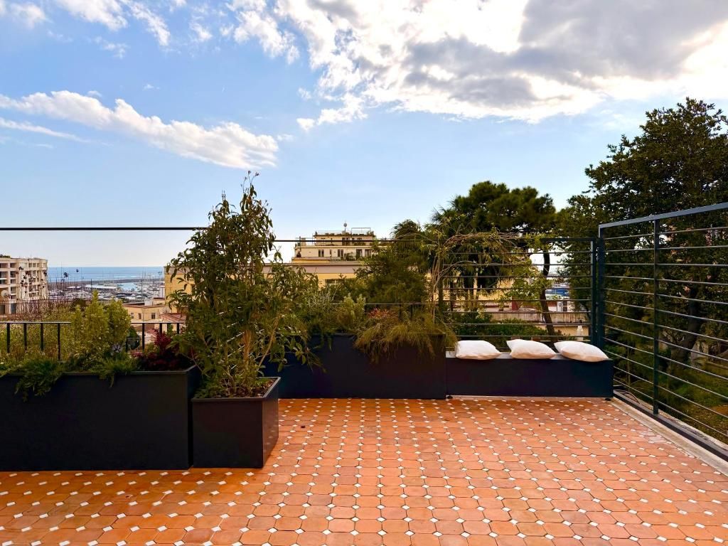 Una terrazza sul tetto con piastrelle in terracotta, piante in vaso e vista sulla città.