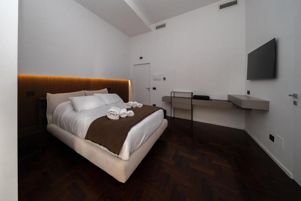 A modern hotel room with a large bed, a bedside table, a flat-screen TV, and a built-in desk.