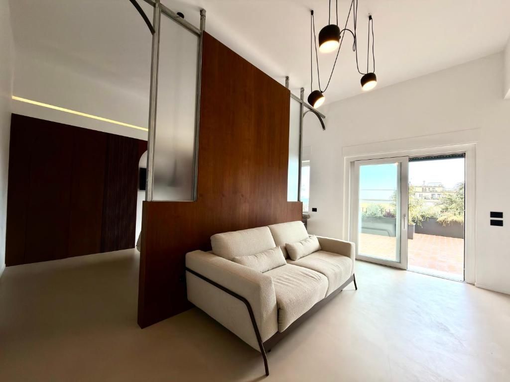Un salon moderne avec un canapé, un mur d’accent en bois et une porte-fenêtre coulissante donnant sur un espace extérieur.