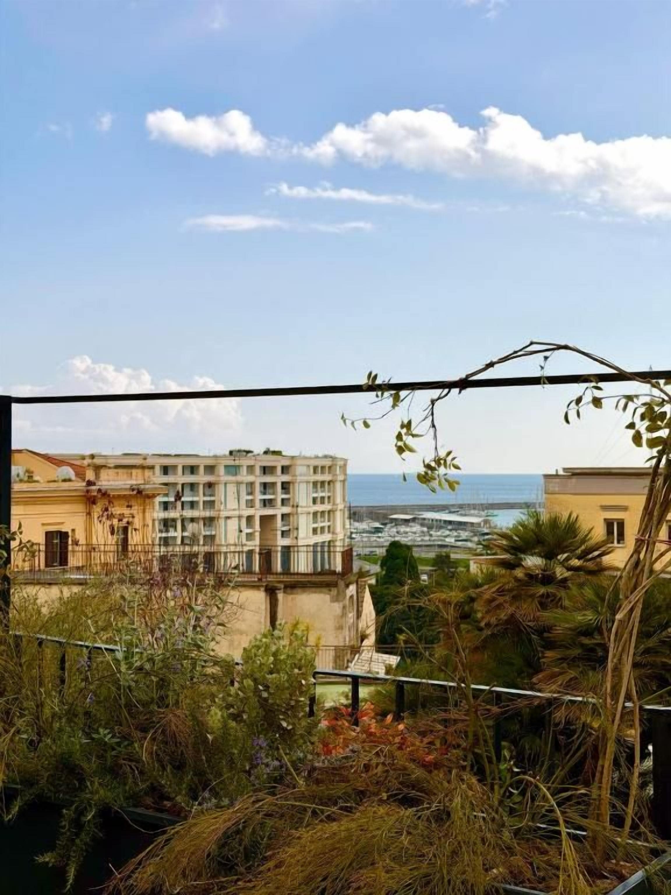 Un balcon offrant une vue sur le paysage urbain de la côte, avec ses bâtiments et la mer.