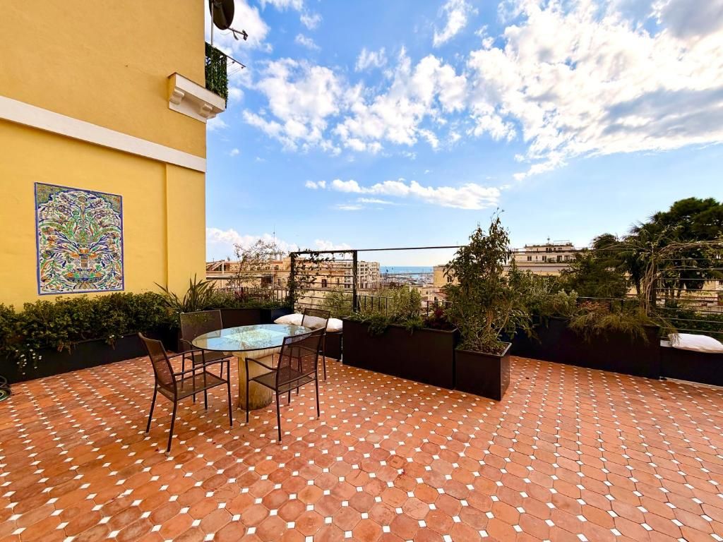 A terrace with a tiled floor, a round table with chairs, and a view of the cityscape.