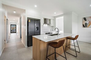 Une cuisine moderne dotée d’un îlot central, d’appareils électroménagers en acier inoxydable et d’un design minimaliste.