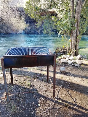 Ein Grill im Freien mit einem Fluss im Hintergrund.
