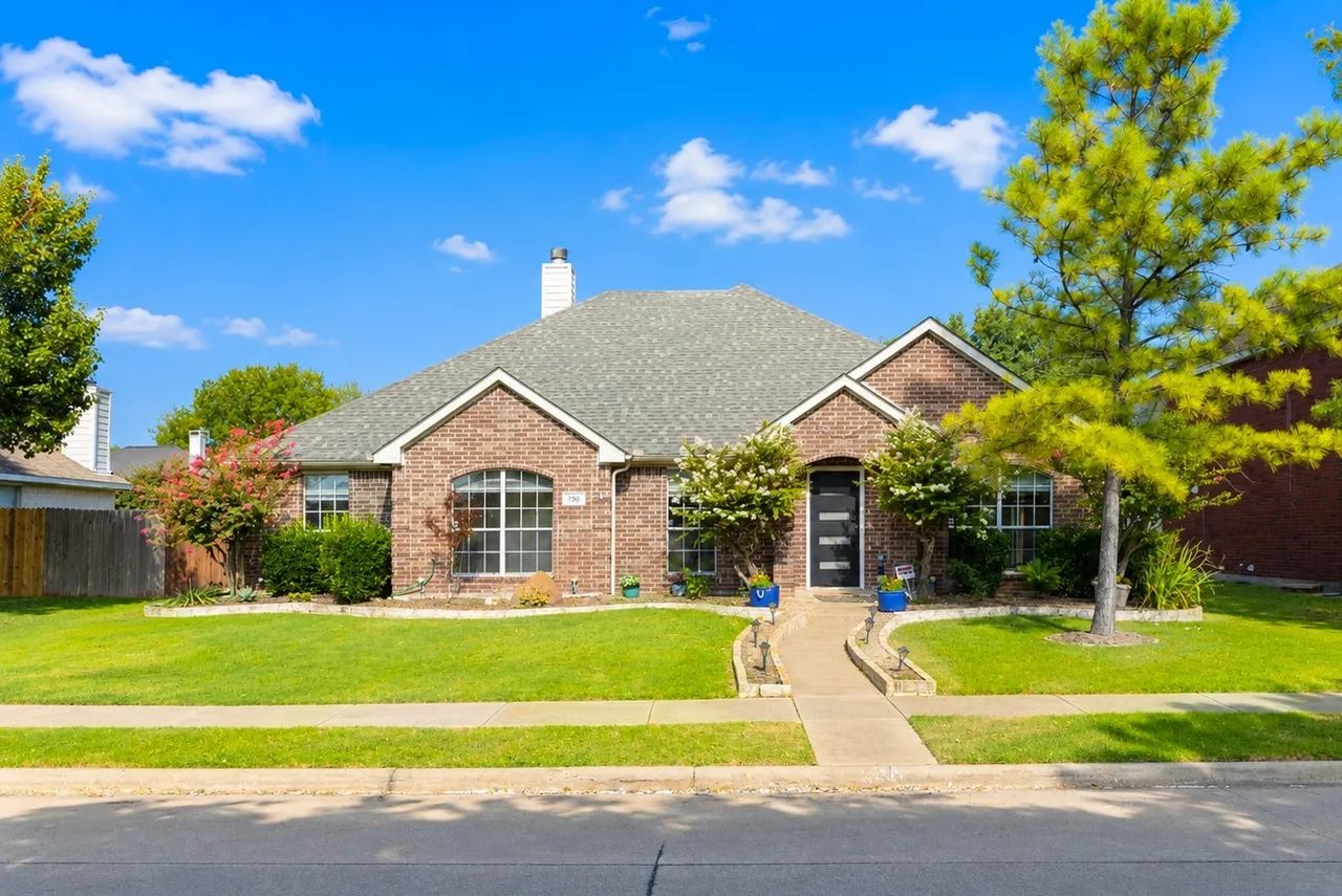 A two-story brick house with a front yard, a driveway, and a mailbox.