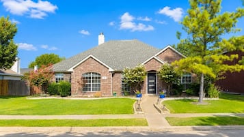 A two-story brick house with a front yard, a driveway, and a mailbox.