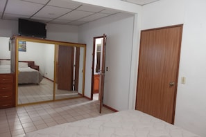 A bedroom with a bed, a wardrobe, a mirror, and a television. - 4BR/4BA Comfortable Home with 2 Private Suites in Santa Tecla (Santa Tecla)