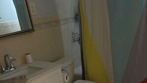 A bathroom with a toilet, sink, and shower area. - Welcoming 3-bedroom house in Asbury Park Close to Downtown & Beach (Asbury Park)