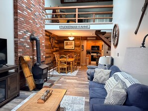 A cozy interior with a loft area, a dining set, and a sofa with decorative pillows. - Penthouse. Sleeps9. 1K, 1Q Bdrms, 2 bath + loft w bunks at Seasons in BartlettNH (Bartlett)