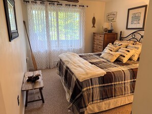 A bedroom with a bed, a wooden dresser, a small table with a teddy bear, and a window with curtains. - Penthouse. Sleeps9. 1K, 1Q Bdrms, 2 bath + loft w bunks at Seasons in BartlettNH (Bartlett)