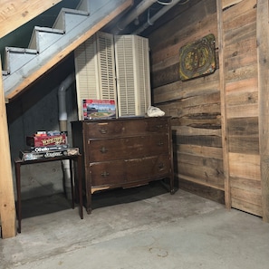 A wooden interior with a staircase, a wooden dresser, and a shelf with board games. - Simpson Station: Historic Train Depot with direct access to recreational trails (Jay)