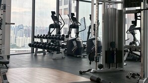 Una palestra con diverse attrezzature per esercizi, ampie finestre e vista sulla città.