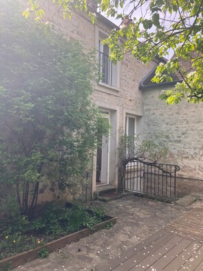 A stone building with a wooden deck and a metal gate. - Charming country house (Villiers-sous-Grez)