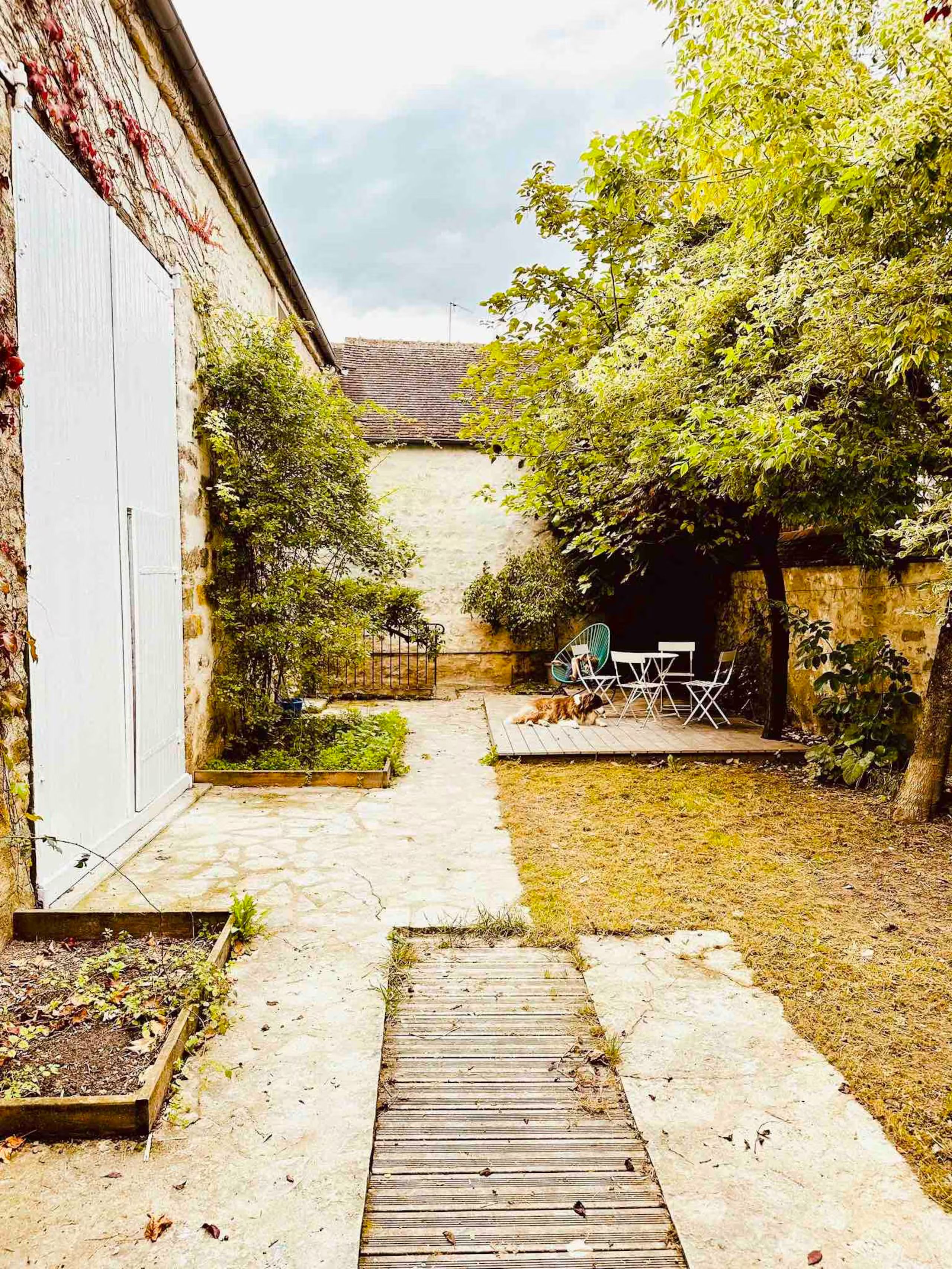 A backyard with a wooden deck, a small garden area, and a seating arrangement.