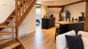 Een modern interieur met een houten trap, een keukenhoek en een zithoek.