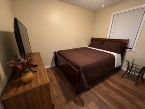 A bedroom with a bed, a wooden dresser, a small table, and a window with blinds. - 6 min drive to Ole Miss & Square--Pet Friendly (Oxford)