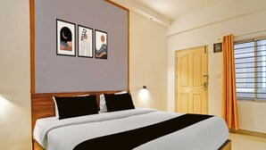Ein Hotelzimmer mit einem Bett, einer Tür und einem mit Vorhängen versehenen Fenster.