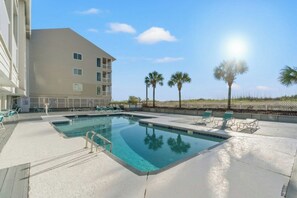 A swimming pool with lounge chairs and a building with multiple balconies. - 3BR Pelicans Watch 110- Pool- 3BR In Shore Drive (Myrtle Beach)