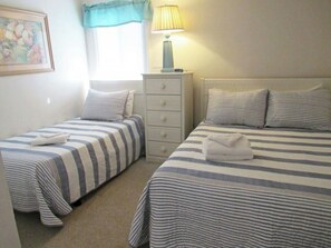 A hotel room with two beds, a nightstand, a lamp, and a painting on the wall. - 3BR Pelicans Watch 110- Pool- 3BR In Shore Drive (Myrtle Beach)