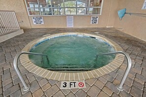 Ett bubbelbad med en skylt som anger ett djup på 3 fot, omgivet av en kakelbeklädd terrass och ett fönster med säkerhetsskyltar.