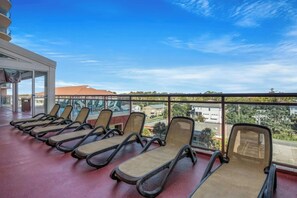 Een rij ligbedden op een balkon met vrij uitzicht op de omgeving.