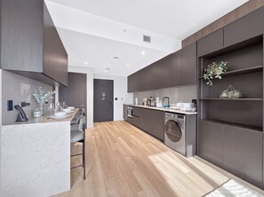 A modern kitchen with a central island, built-in appliances, and a dining area with a long table. - 42nd Floor Miami Studio with Skyline Views (Miami)