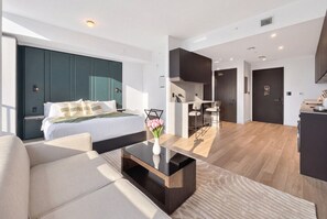 Une chambre d’hôtel moderne équipée d’un lit, d’un canapé, d’une table basse et d’un coin repas avec des chaises et une table.