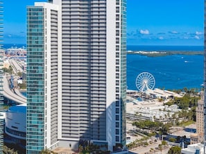 A high-rise hotel with a modern design, featuring a prominent vertical structure and a large Ferris wheel in the background. - 42nd Floor Miami Studio with Skyline Views (Miami)