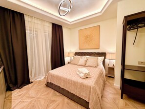 Una habitación de hotel con cama, una lámpara en el techo, una obra de arte colgada en la pared y un perchero.