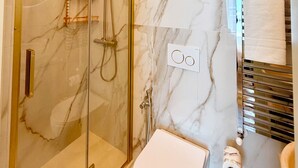 Ein modernes Badezimmer mit einer gläsernen Dusche, einer weißen Toilette und einem Handtuchhalter.
