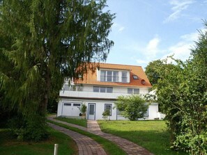 Ein zweistöckiges Haus mit einem Ziegeldach, einer Haustür und einer gepflasterten Auffahrt zum Eingang.