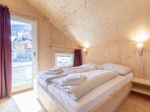 Ein Schlafzimmer einer Holzhütte mit Bett, Fenster und Tür.