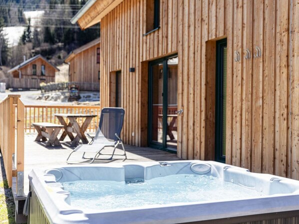 A wooden cabin with a hot tub, outdoor seating, and a deck. - One-bedroom Cabin (Sankt Georgen am Kreischberg)
