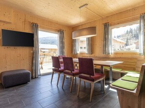 A wooden interior with a dining area, a flat-screen TV, and large windows. - One-bedroom Cabin (Sankt Georgen am Kreischberg)
