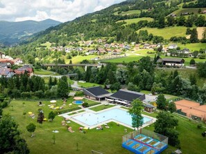 A residential area with a swimming pool, tennis court, and houses surrounded by greenery. - One-bedroom Cabin (Sankt Georgen am Kreischberg)
