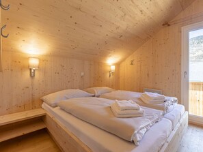 A wooden room with two beds, each with pillows and towels, and two wall-mounted lamps. - One-bedroom Cabin (Sankt Georgen am Kreischberg)
