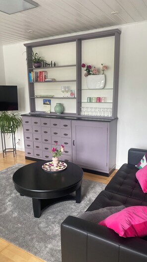A living room with a grey cabinet, a black coffee table, and a black sofa with a pink pillow. - Romantic Vacation Home Galmbacher (Braubach)