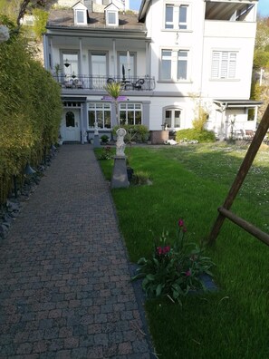 A pathway leading to a white building with a balcony and a statue in the front yard. - Romantic Vacation Home Galmbacher (Braubach)